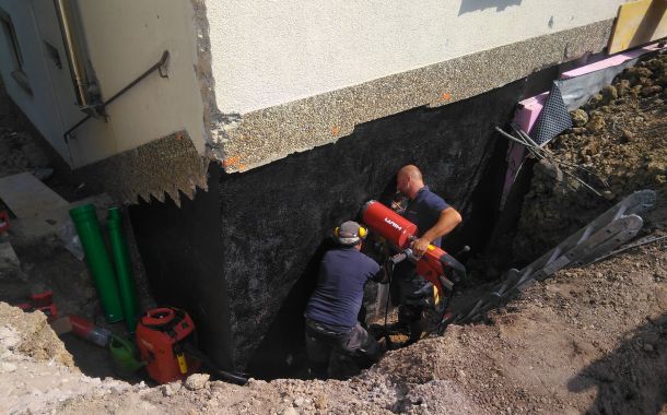 Arbeiter führen Sanierungsarbeiten am Fundament eines Hauses durch.
