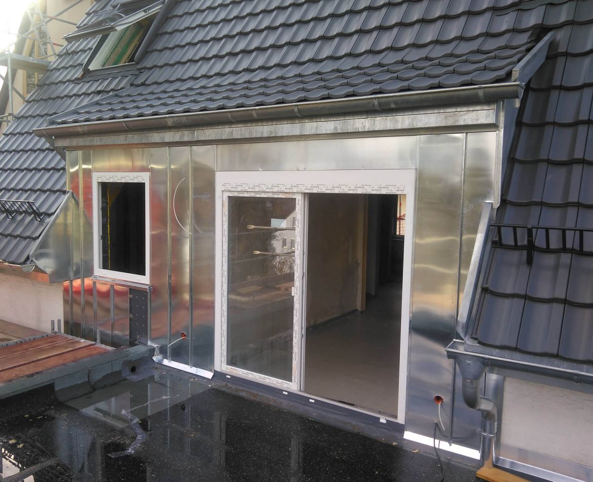 Sanierte Balkonanlage mit grauem Bodenbelag und Edelstahlgeländer an einem städtischen Wohngebäude.