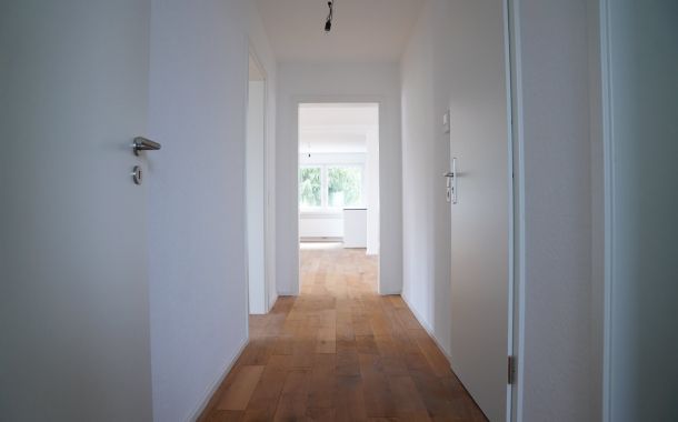 Modernisierter Flur in einem Altbau mit Parkett und weiß gestrichenen Wänden nach der Sanierung.